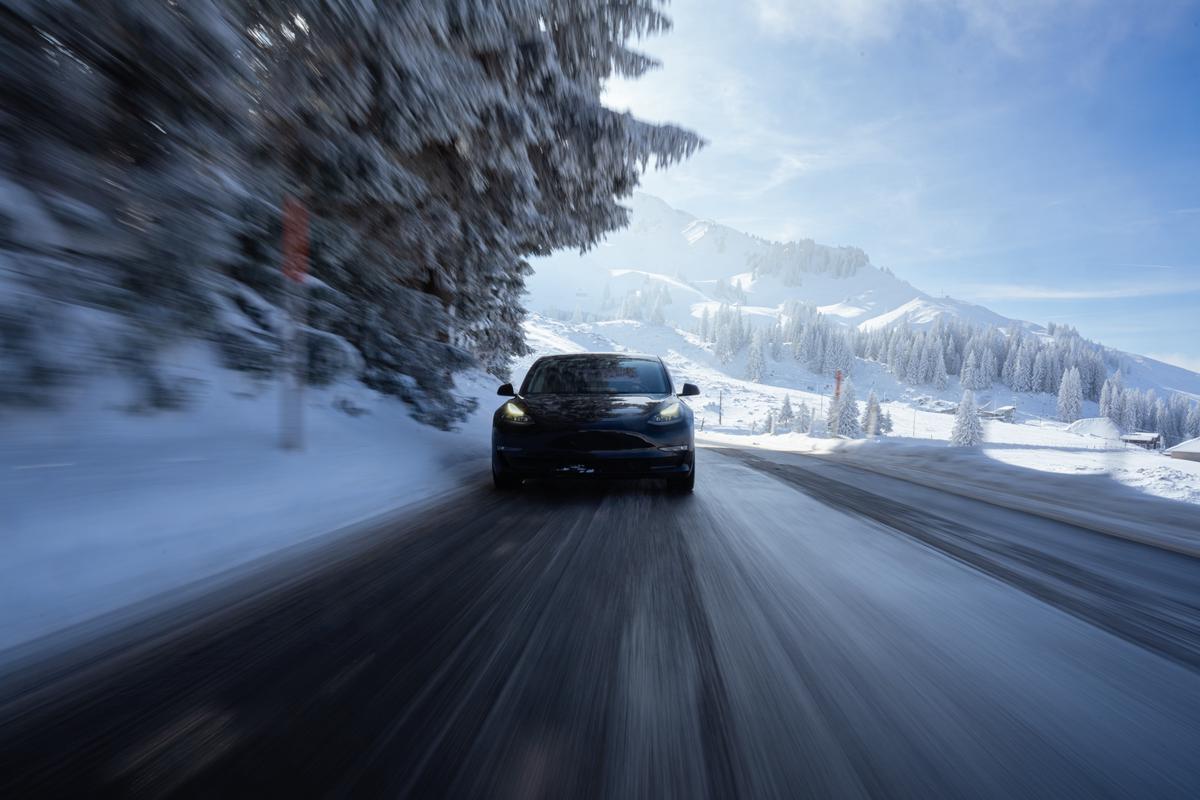 A Tesla car driving through a snowy landscape, showcasing the winter-friendly features of the vehicle.