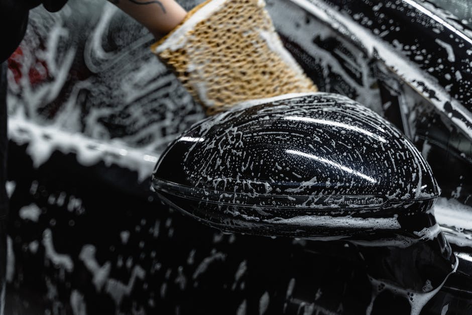 A person cleaning a Tesla car with a microfiber cloth